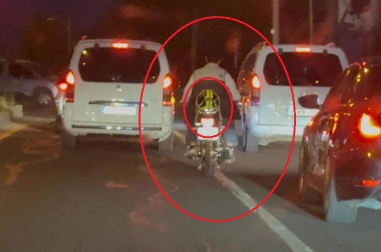 Motosiklet sürücüsü trafikte kaskı başına takması yerine arkasına bağladı